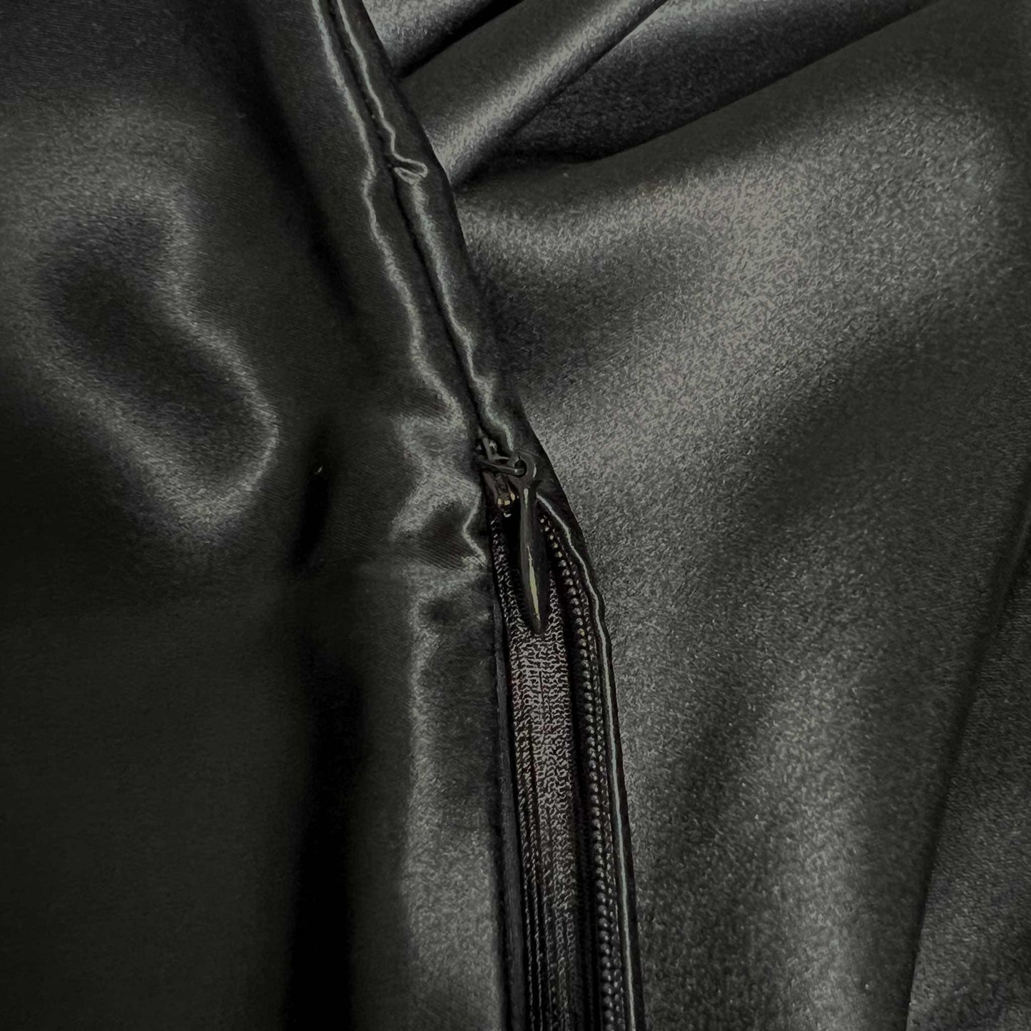 Close-up of a black zipper on a silk pillowcase