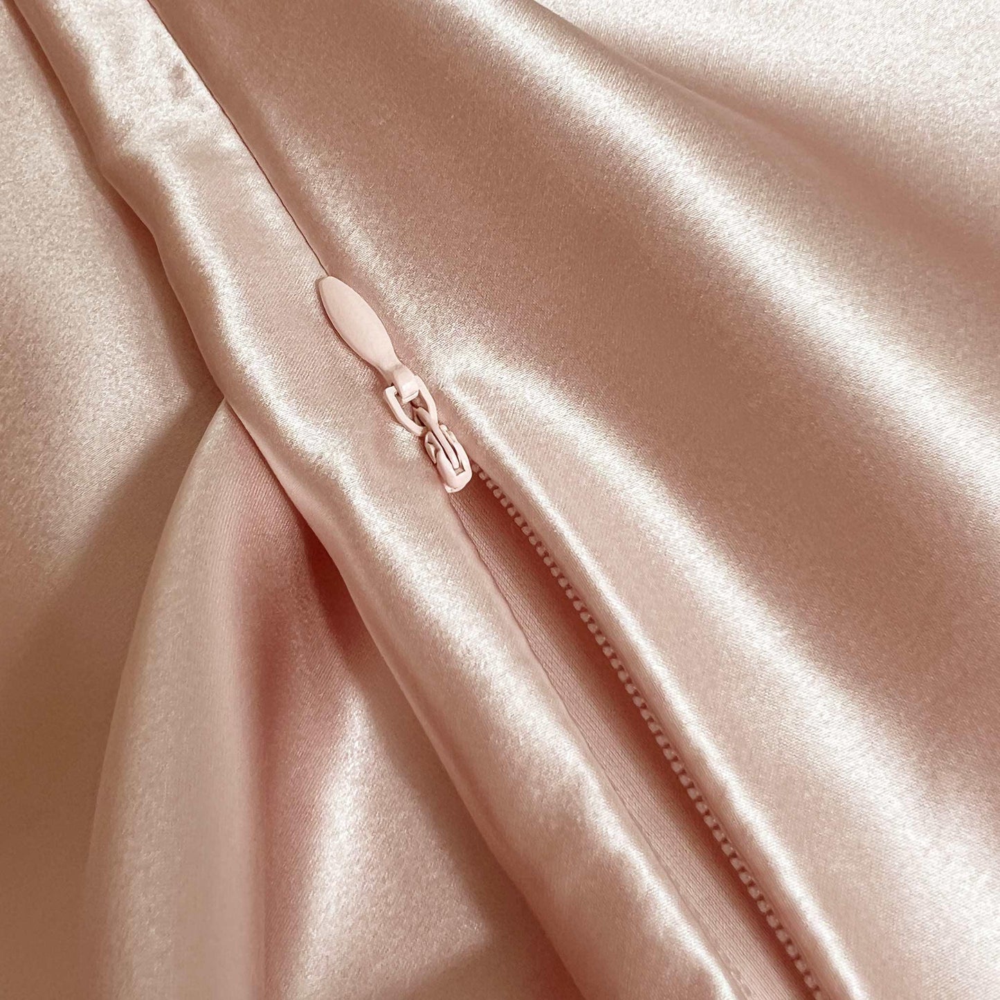 Close-up of a pink rose gold 100% mulberry silk fabric with a zipper