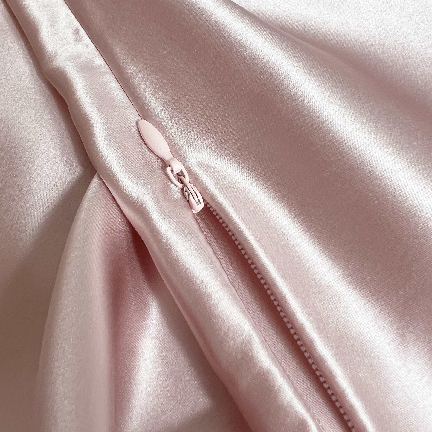 Close-up of a pink silk fabric with a zipper