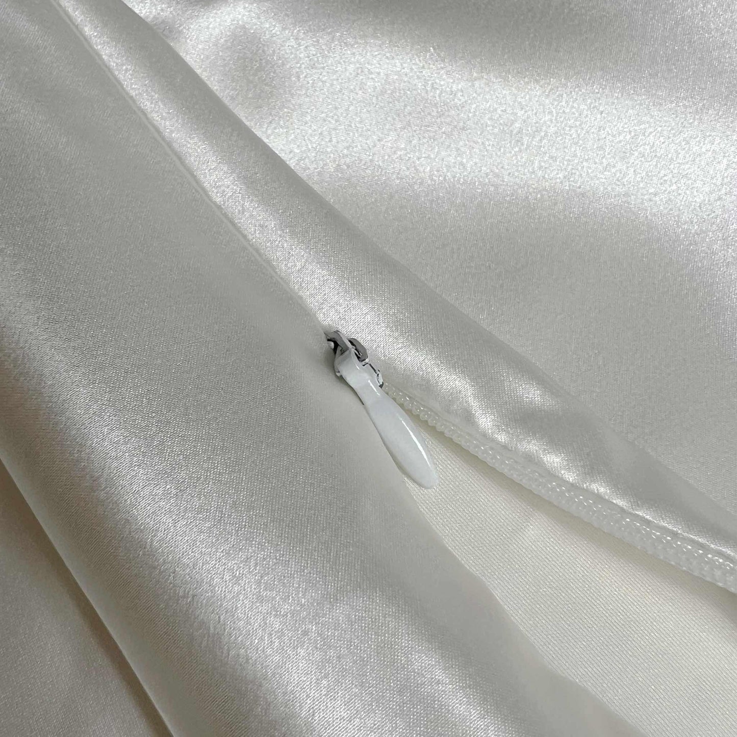 Close-up of a white silk pillow case zipper