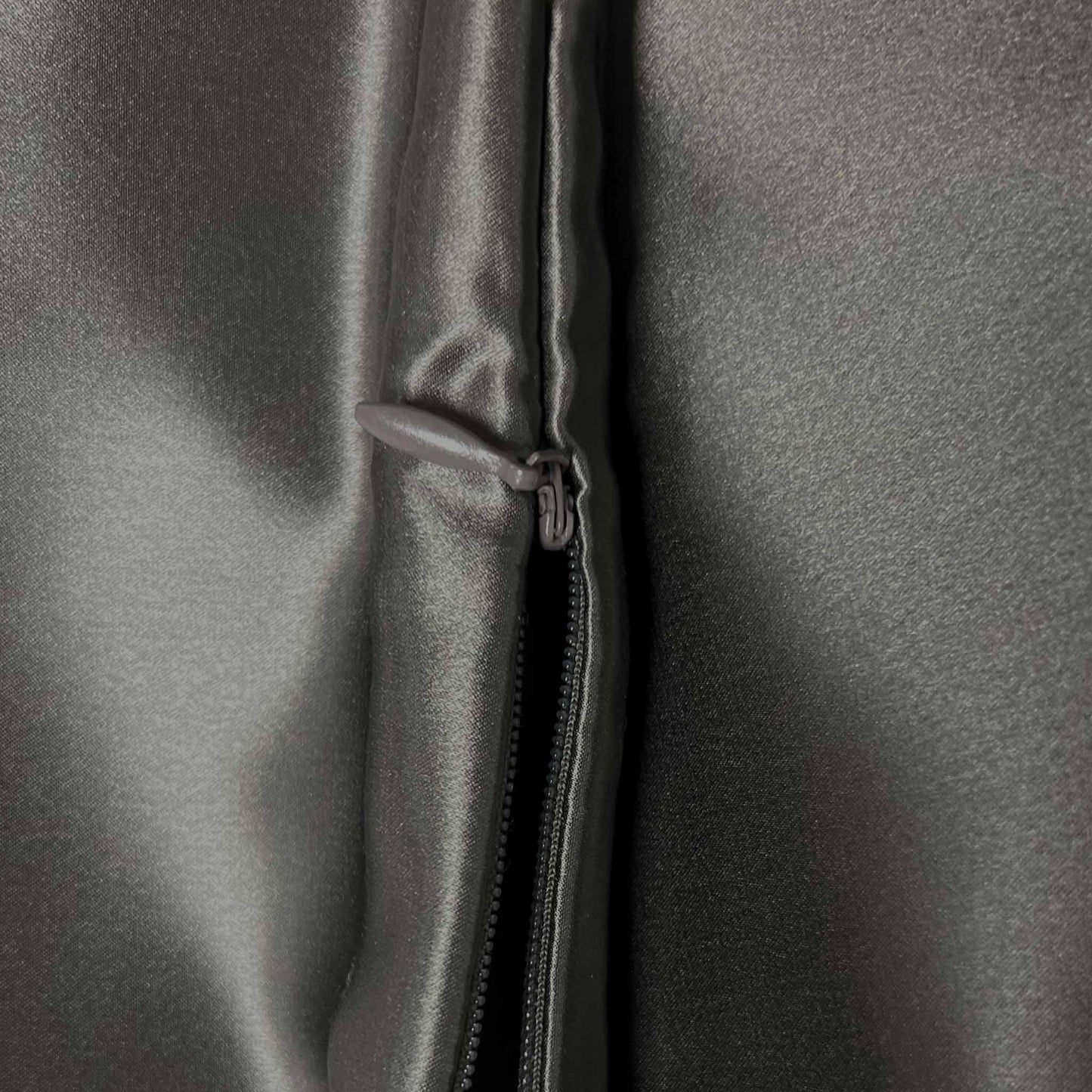 Close-up of a zipper on a gray silky fabric surface