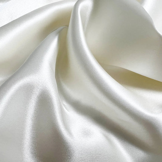 Close-up of smooth, white mulberry silk fabric with soft folds.
