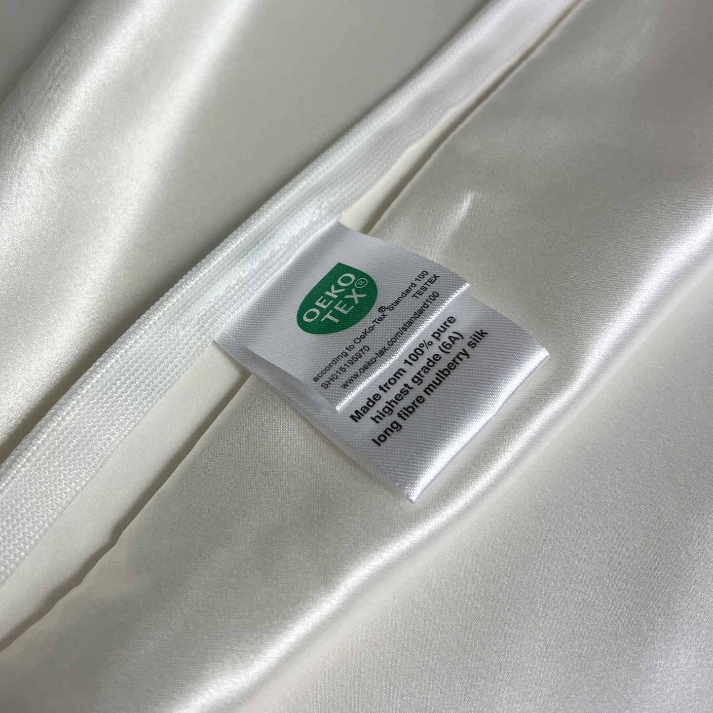 Silky white pillow case with a label featuring the OEKO-TEX logo