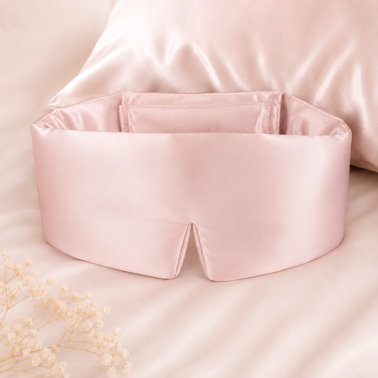 Blush Petal 22 momme mulberry silk eye mask displayed on soft silk bedding