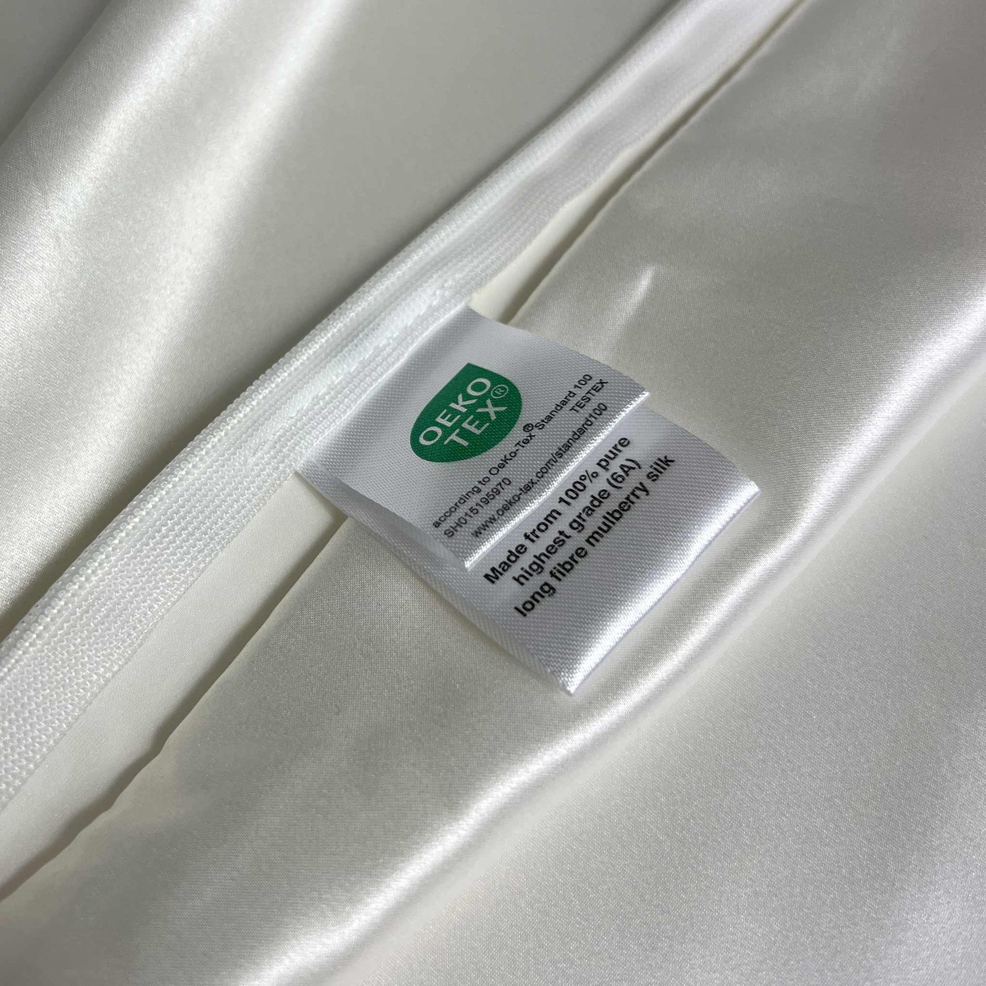 Silky white pillow case with a label featuring the OEKO-TEX logo